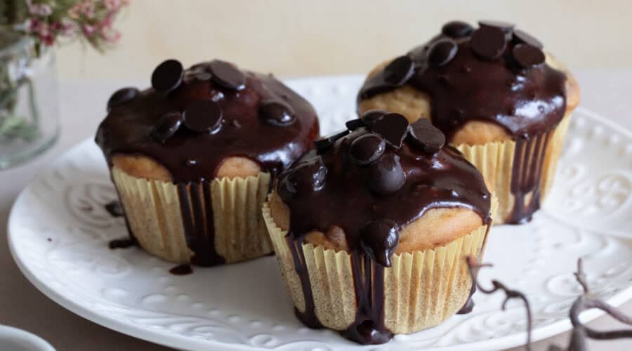 Cupcakes mit Schokoladenglasur und Schokoladenstückchen auf weißem Teller, frisch gebacken, vegetarisch, glutenfrei, lecker, süßes Gebäck, Backkunst, Konditorei, Genuss, Backen, Desserts, Feinbäckerei, Torten, Nascherei, Patisserie, süßer Snack, backfrisch, handgemacht, Österreich, feines Gebäck, Vanille, Schokolade, Backtradition, feine Konditorei, Konditorenkunst, Süßigkeiten, Dessertideen, Kaffeeklatsch, Kaffee und Kuchen, süßer Genuss, Backliebe, Kekse, kleine Torten, feinstes Gebäck, Kaffeezeit, Genussmomente.