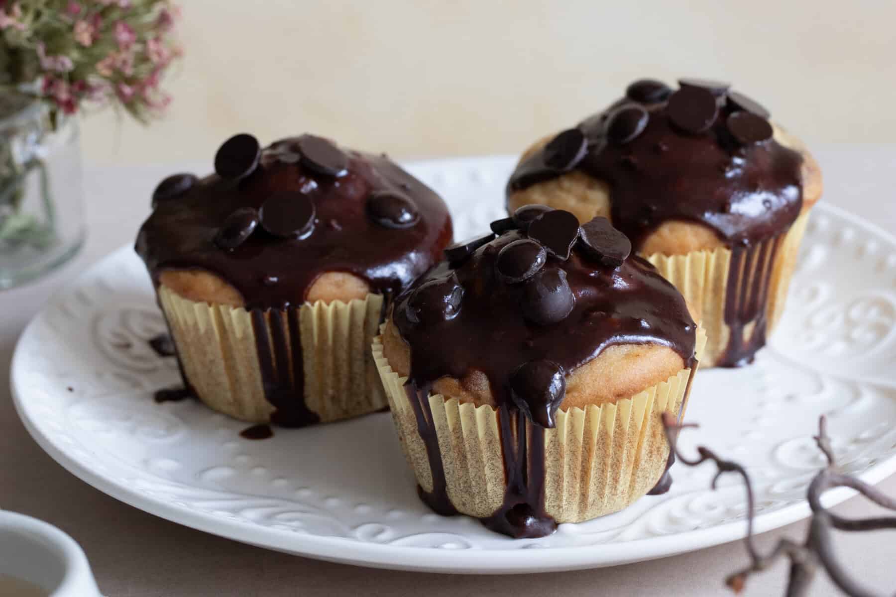 Cupcakes mit Schokoladenglasur und Schokoladenstückchen auf weißem Teller, frisch gebacken, vegetarisch, glutenfrei, lecker, süßes Gebäck, Backkunst, Konditorei, Genuss, Backen, Desserts, Feinbäckerei, Torten, Nascherei, Patisserie, süßer Snack, backfrisch, handgemacht, Österreich, feines Gebäck, Vanille, Schokolade, Backtradition, feine Konditorei, Konditorenkunst, Süßigkeiten, Dessertideen, Kaffeeklatsch, Kaffee und Kuchen, süßer Genuss, Backliebe, Kekse, kleine Torten, feinstes Gebäck, Kaffeezeit, Genussmomente.