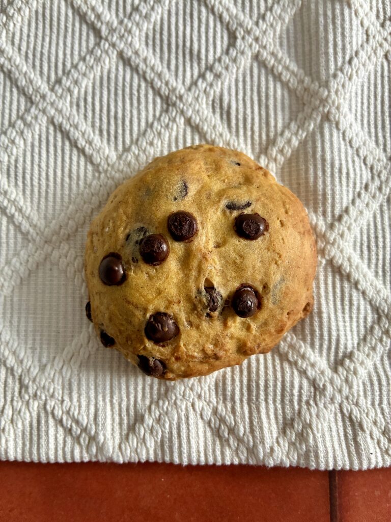 Saftiger veganer Kürbiskeks mit Schokoladestückchen auf Stoffunterlage.